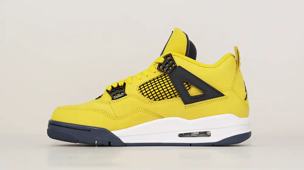 A front view of the inner mesh panel on the right shoe of the Jordan 4 Retro ‘Lightning’ (2021), showcasing the yellow leather upper and the black breathable mesh vents