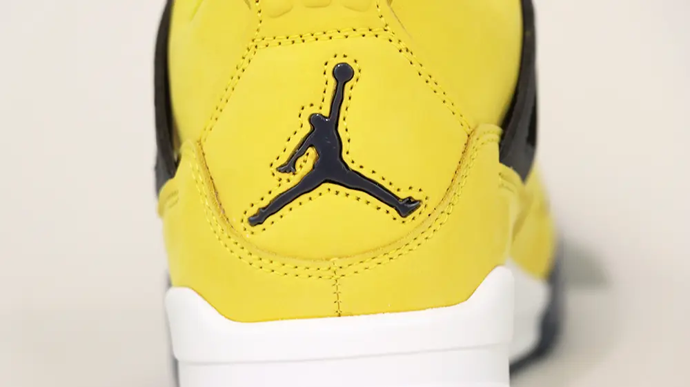 A rear view of the heel on the Jordan 4 Retro ‘Lightning’ (2021), featuring yellow suede material and a black Jumpman logo.