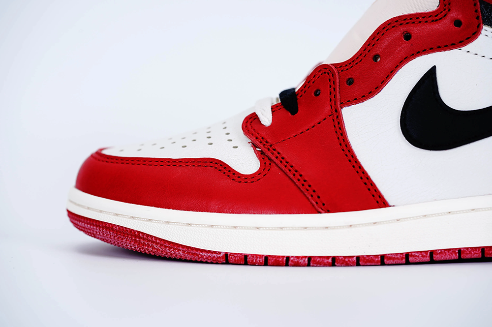 A side view of the front half of the left shoe of the Jordan 1 Chicago High OG ‘Lost & Found,’ highlighting its red leather toebox material.