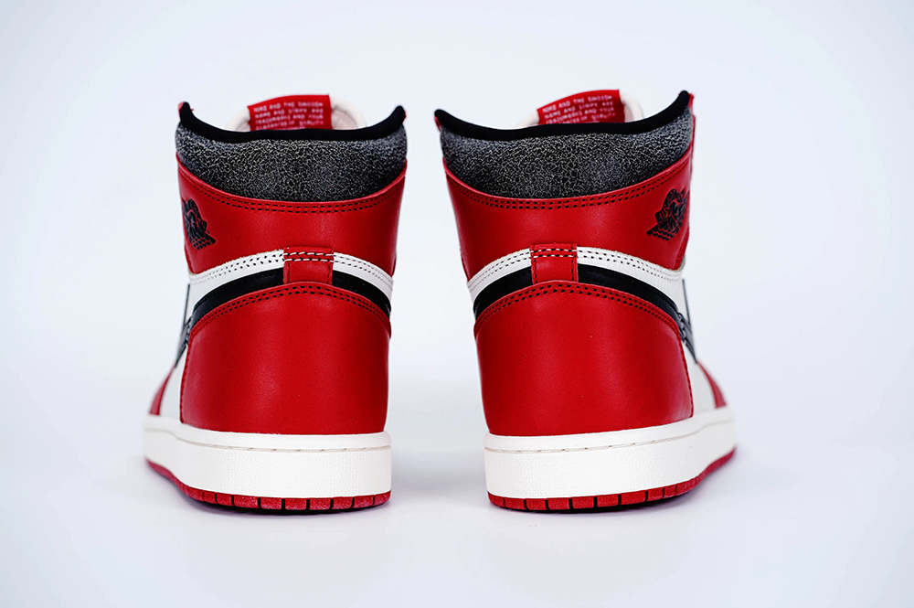 A rear view of both shoes of the Jordan 1 Chicago High OG ‘Lost & Found,’ showcasing the cracked black leather effect on the heels