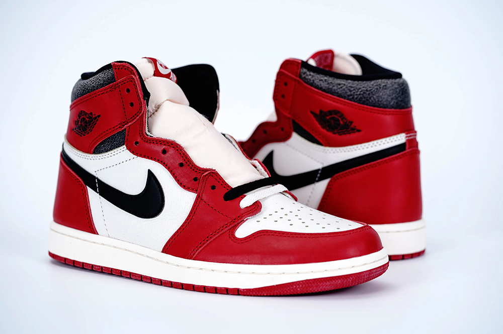 A side-by-side view of both shoes of the Jordan 1 Chicago High OG ‘Lost & Found,’ highlighting its red, white, and black cracked leather material.