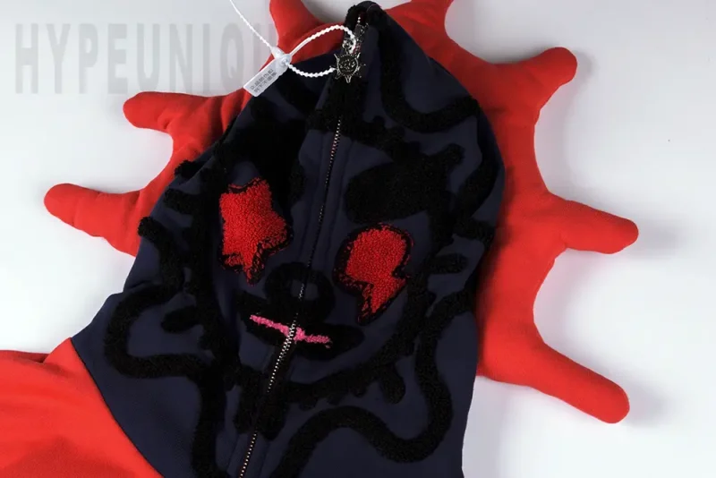 Most noteworthy detail: the red protrusions and fuzzy embroidered sun emoji on the hoodie.