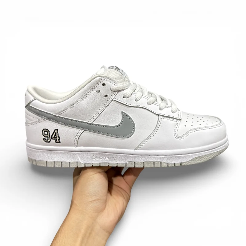Opposite side view of white low-top sneaker showing embroidered number detail and layered leather panels