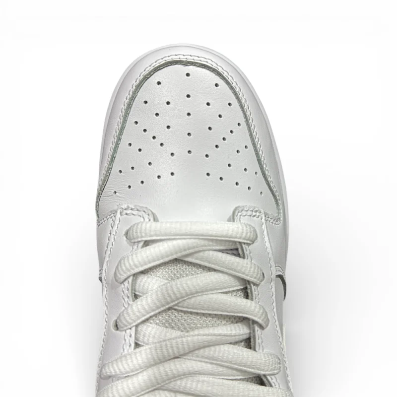 Top-down view of white sneaker toe box with evenly spaced perforations and flat laces