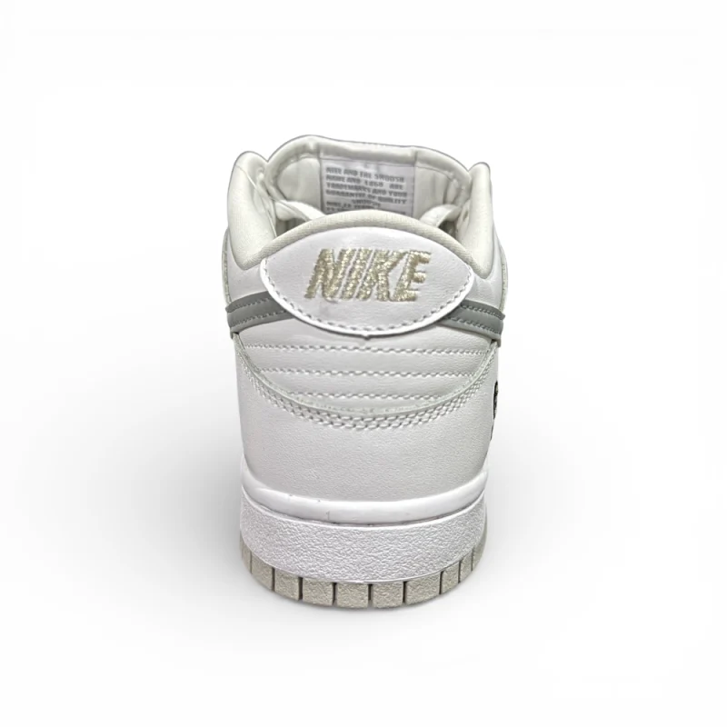 Rear view of white sneaker showing heel stitching, padded collar, and embossed heel branding