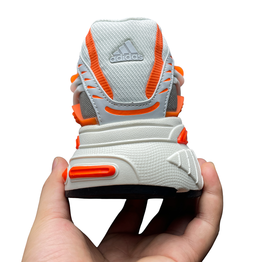 Close-up of a sneaker's mesh upper with orange and gray accents, highlighting textured fabric, layered design, and dynamic angles.