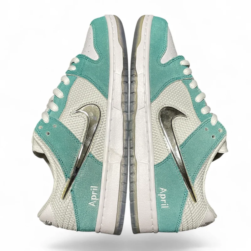 Close-up of a sneaker's tongue in white mesh, with teal suede accents and white laces crossing diagonally.