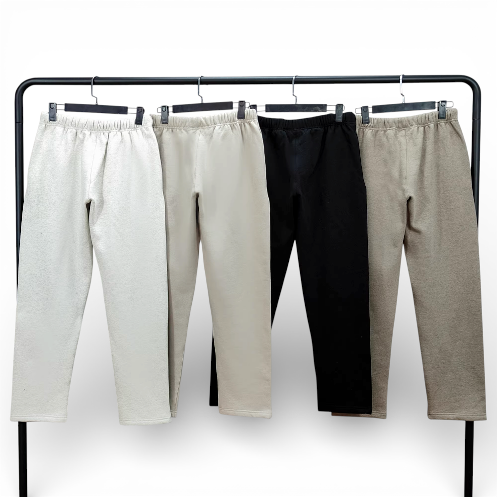 Four pairs of sweatpants in beige, cream, black, and grey cotton on hangers.