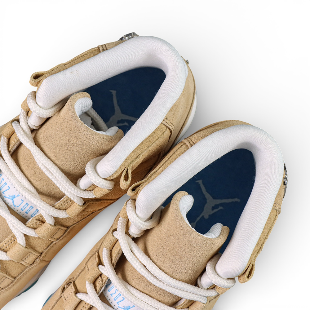 Close-up of tan suede sneakers with white laces and cushioned blue insoles.