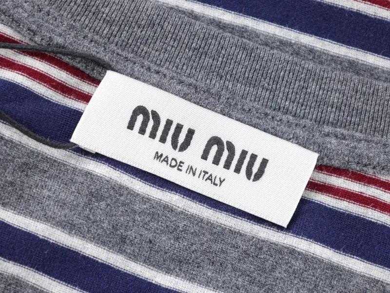 Gray fabric with blue and red stripes, featuring a white label stitched on, displaying "MIU MIU" and "Made in Italy."