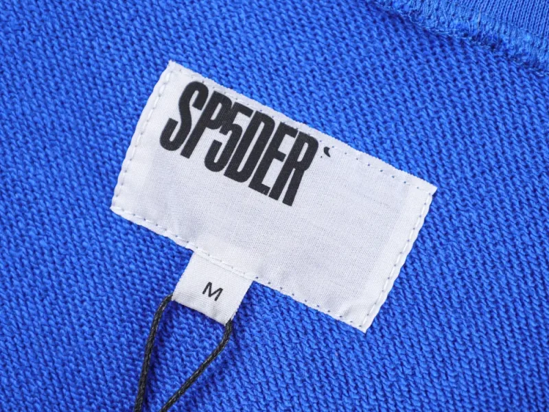 Blue knitted fabric with a white label displaying the text "SP5DER".