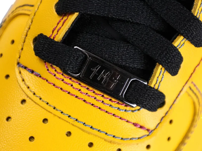 Yellow leather shoe with black laces and metal lace tag holder.