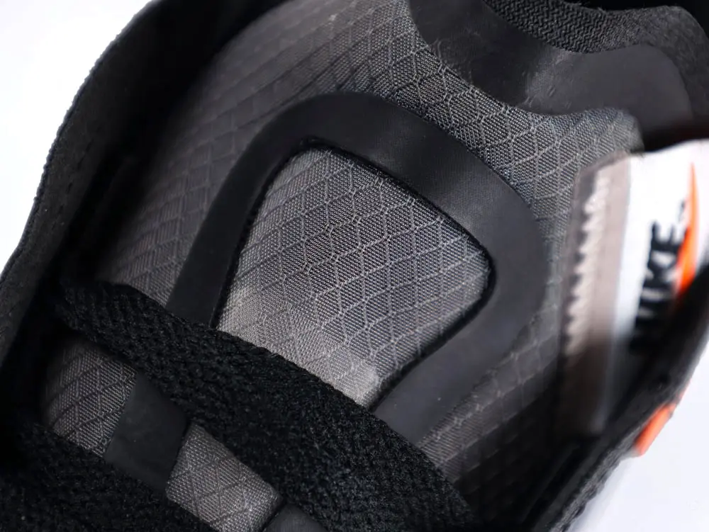 Close-up of a gray sneaker with black laces, showcasing textured fabric material.