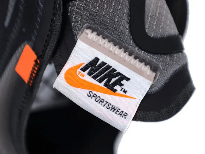 Close-up of a black and gray fabric sneaker with an orange detail and label.