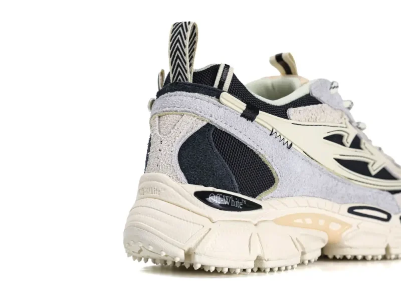 Black and white sneaker with suede and mesh materials, featuring branded heel detail.