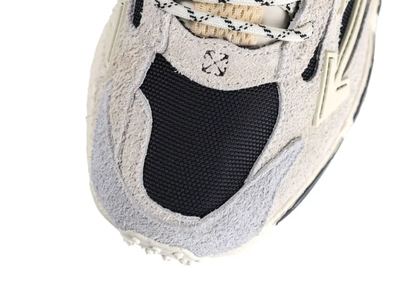 Close-up of a sneaker's beige suede upper with black mesh detailing.