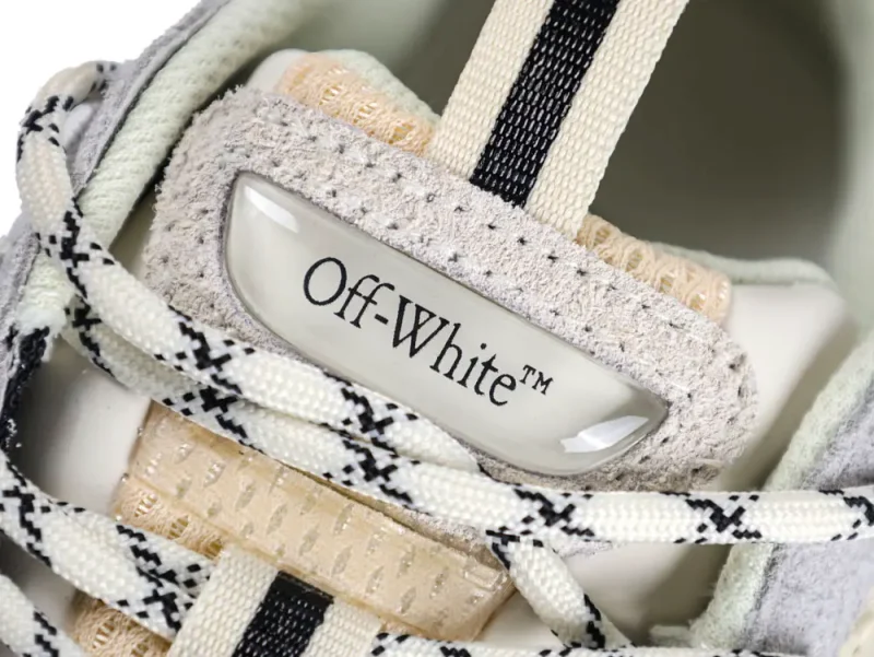 Close-up of a gray suede sneaker with black-and-white laces, labeled "Off-White".