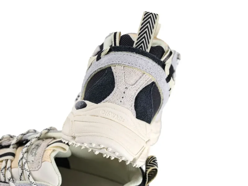 Beige and black sneaker heel with suede and mesh materials, herringbone pull tab.