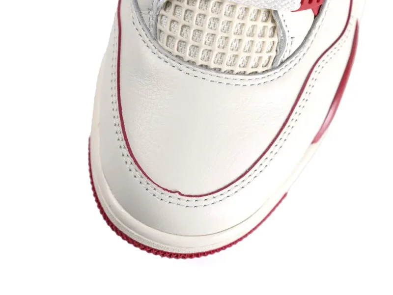 White leather sneaker with red trim and mesh detailing on the upper.