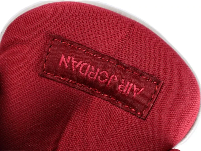 Red fabric shoe tongue with embroidered red label, featuring stitched details.