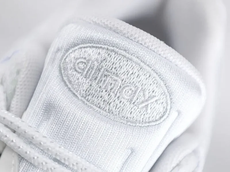 White leather sneaker with detailed stitching and side embroidered logo in focus.
