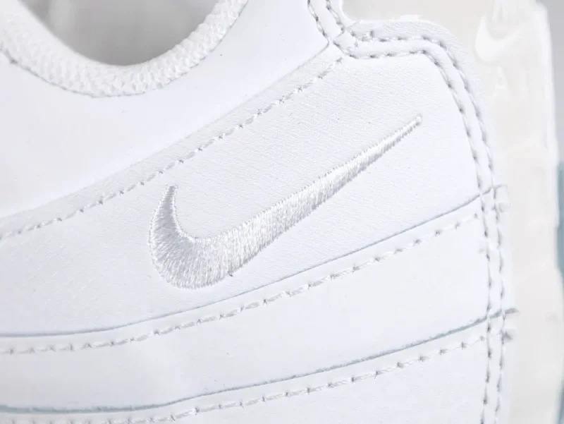 White leather sneaker with detailed stitching and side embroidered logo in focus.