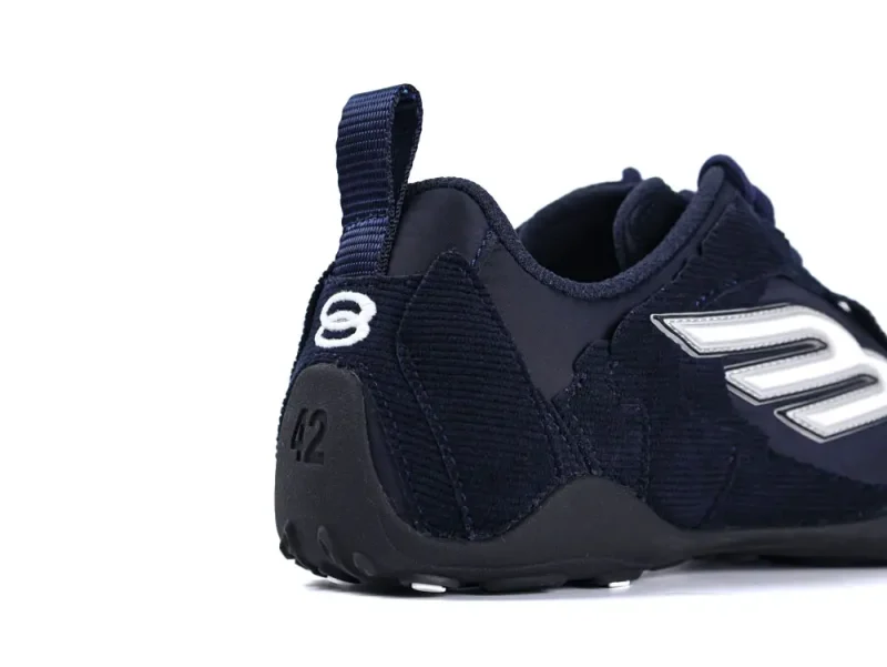 Navy fabric sneaker with textured material and white emblem on the heel.