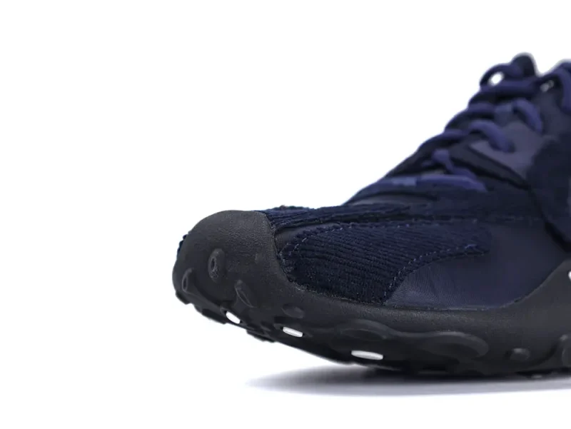 Navy blue sneaker with fabric upper and black rubber sole, close-up view.
