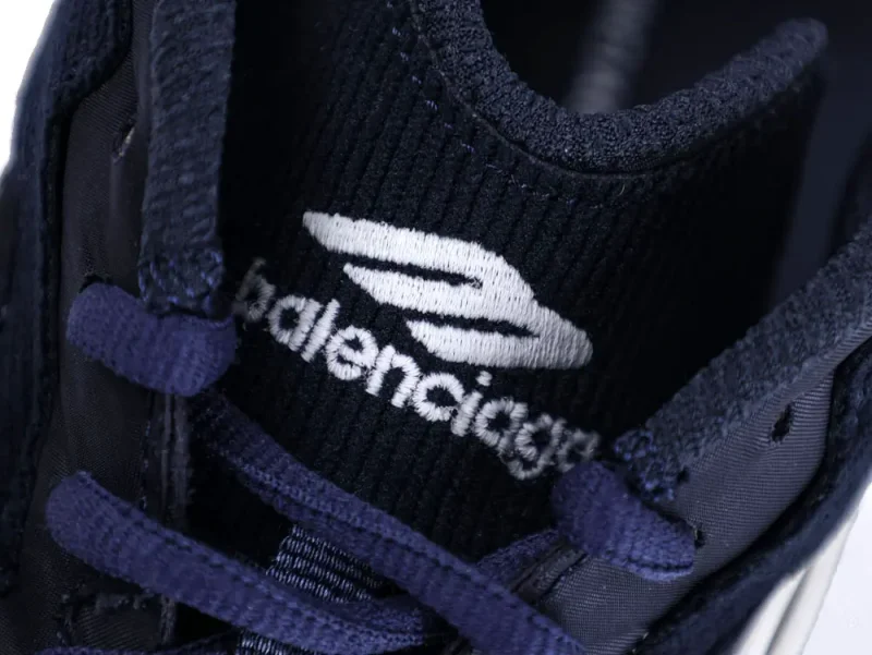 Close-up of a navy blue fabric sneaker tongue with brand logo embroidery.