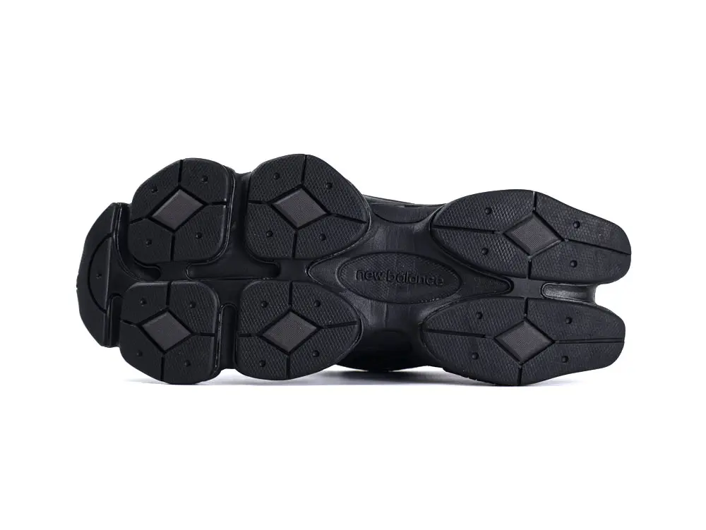 Black rubber sneaker outsole with multi-pattern grip and New Balance logo in center.