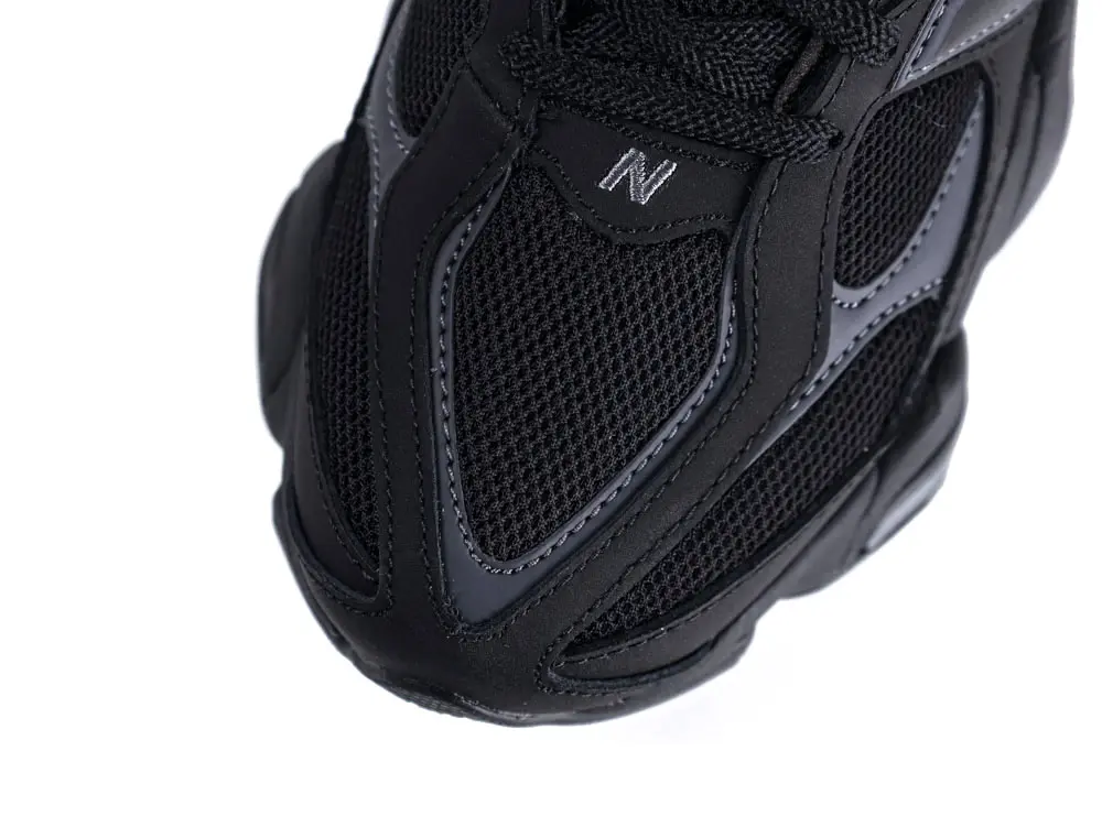 Close-up of black mesh and leather sneaker toe with textured detailing.