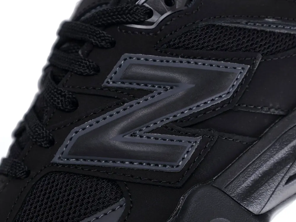 Black sneaker with leather and mesh material featuring a prominent "N" logo detail.