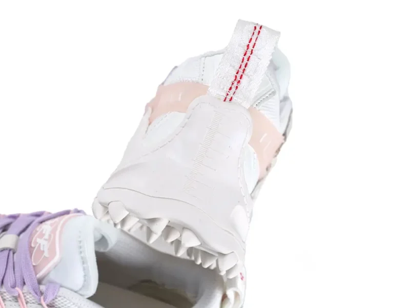 Close-up of white sneaker heel with pink accent, rubber sole, and fabric pull tab.