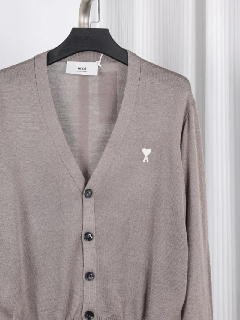 Taupe cardigan made of knit fabric with black buttons and a heart logo.