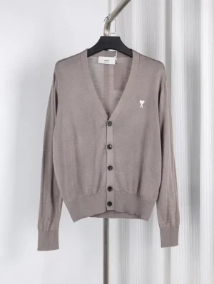 Knit cardigan with black buttons, ribbed cuffs, and hem on hanger.