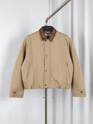 Beige jacket with brown leather collar, featuring zippered pockets and buttoned cuffs.