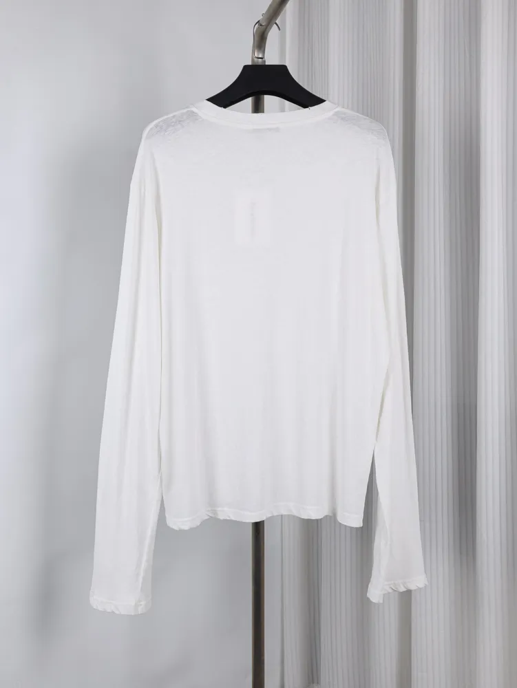 White long-sleeve shirt made of soft fabric, hanging on a black hanger.