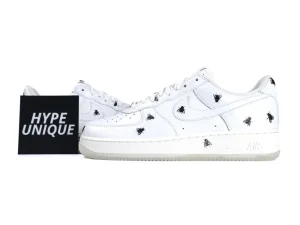 White leather sneakers with black fly design on the sides and toe.
