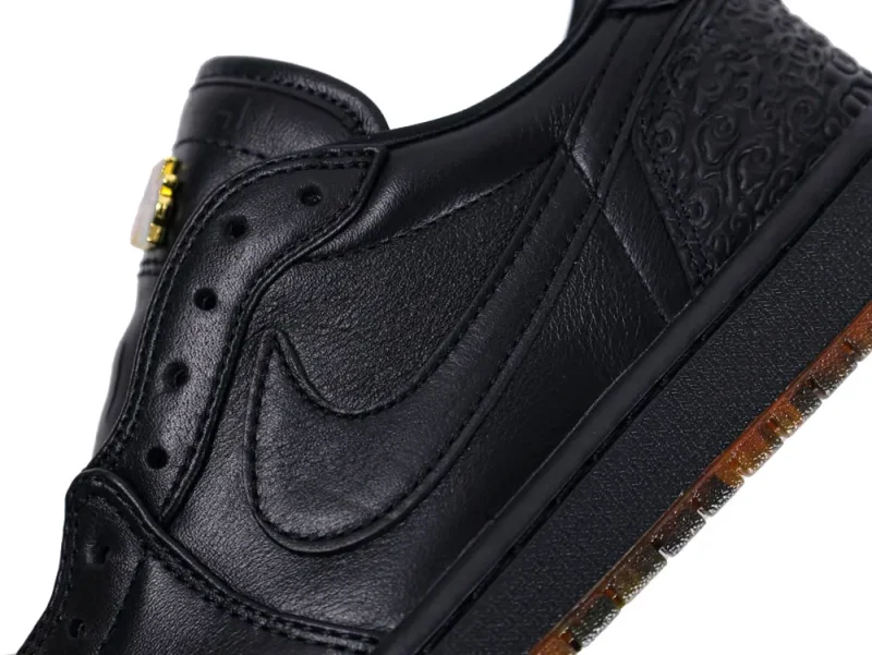 Black leather sneaker with embossed pattern and translucent rubber sole detail.