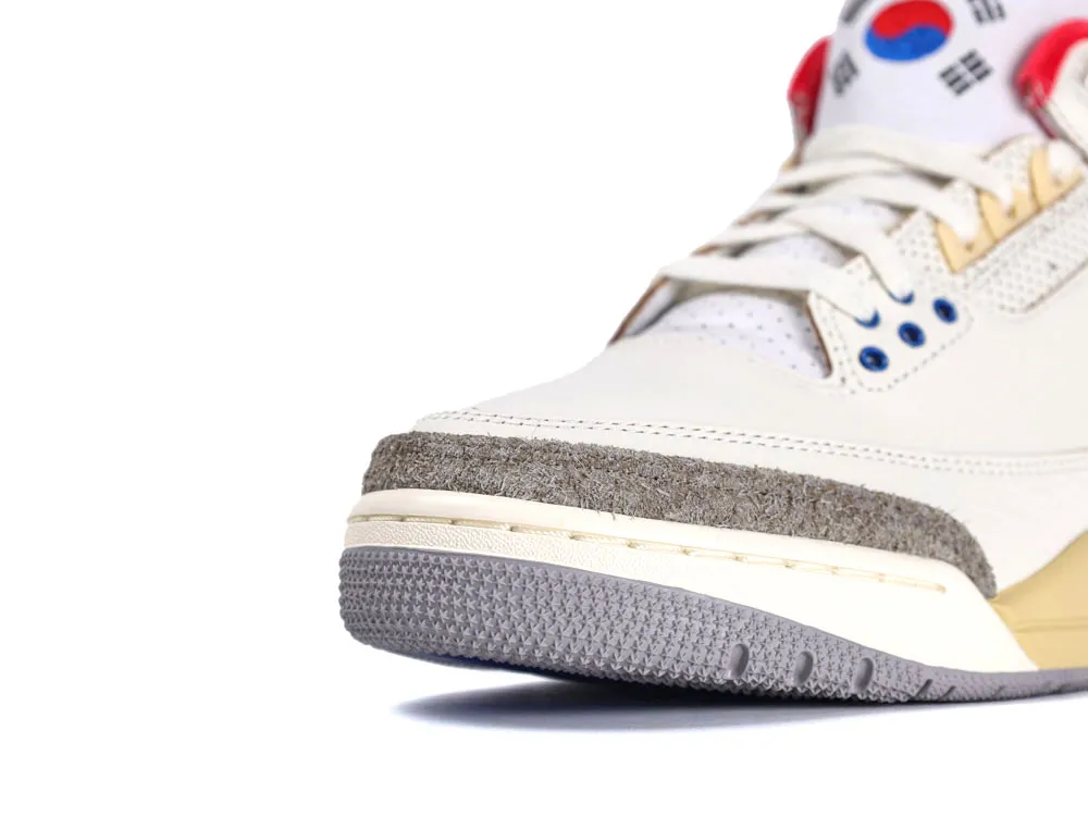 Cream leather sneaker with suede accents and textured grey rubber sole, red and blue details.
