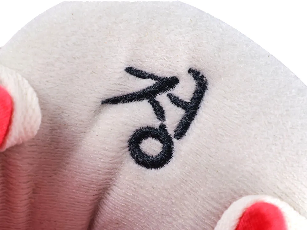 Beige plush material with black embroidered characters, featuring red and white sections.