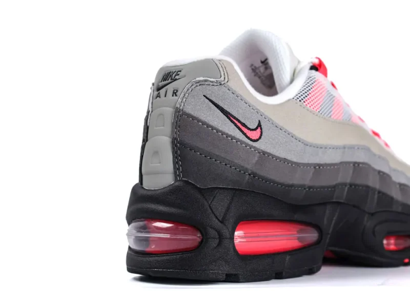 Gray and pink Nike shoe with black sole and red air cushioning.
