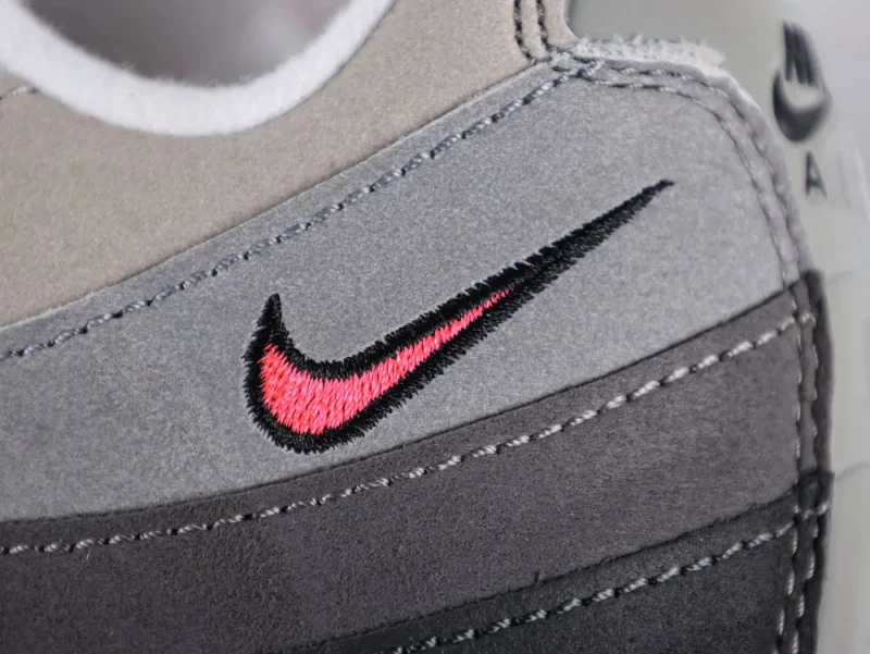 Gray and black suede shoe with pink embroidered logo detail.