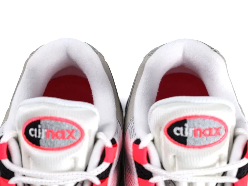 Close-up of sneakers with white mesh, red highlights, and cushioned collars.