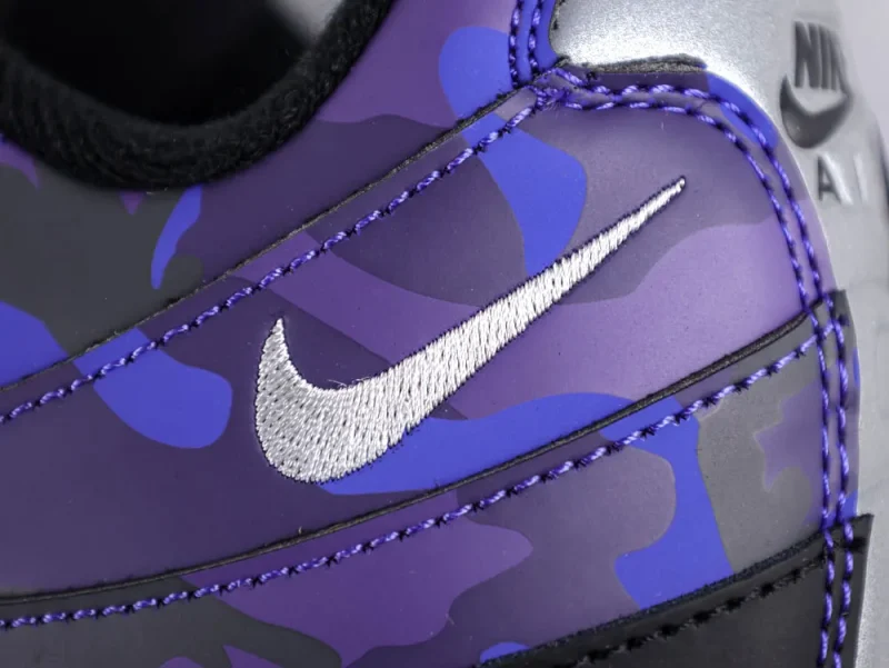 Close-up of purple and blue camouflage shoe with embroidered silver logo.