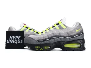 Gray and yellow suede sneakers with mesh upper and black sole displaying "Undefeated."