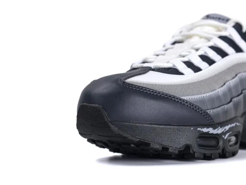Close-up of a black, white, and gray sneaker with mesh and leather materials.