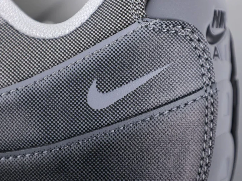 Close-up of gray fabric and leather sneaker with stitched detailing and logo.