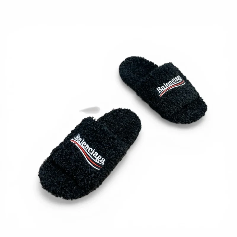 Black fuzzy slippers with embroidered logo, made from soft textured material.