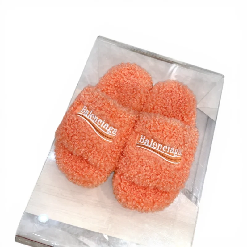 Orange fluffy slippers with embroidered logo on the upper part.